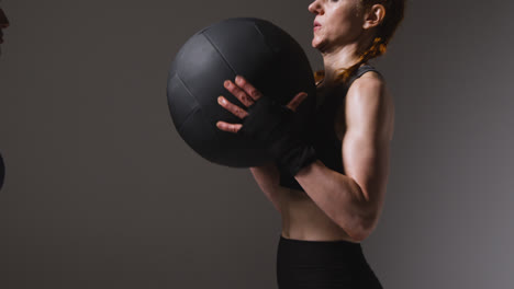 Studioaufnahme-Von-Zwei-Reifen-Frauen-In-Fitnessstudio-Fitnesskleidung,-Die-Gemeinsam-Mit-Einem-Gewichteten-Medizinball-Trainieren